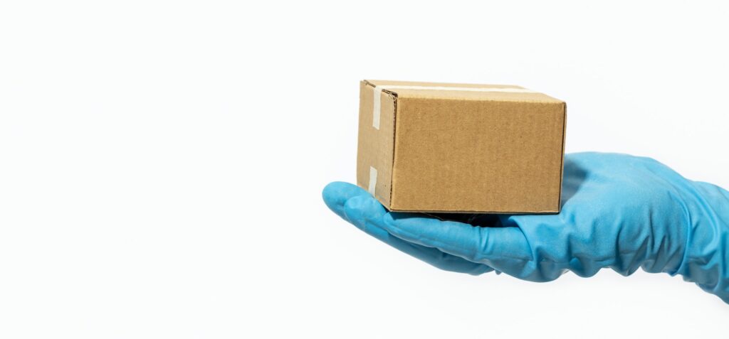 Delivery man holding cardboard box in rubber gloves