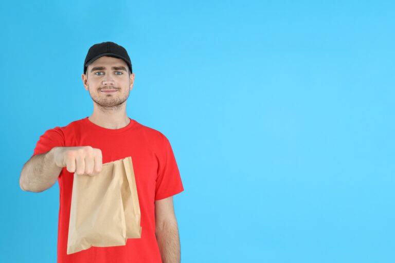 Delivery man holds paper bags on blue background